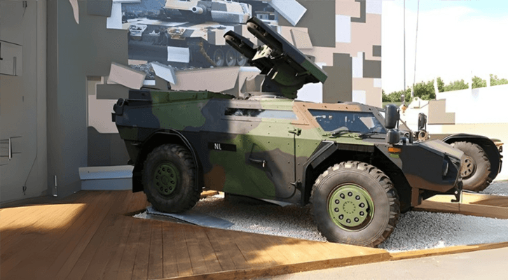 Camouflage armored military vehicle with mounted weapon displayed outdoors for defense and tactical demonstration.