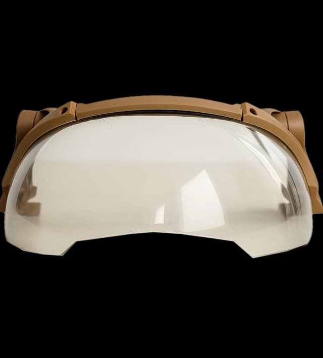 Close-up front view of a tan fragment visor with a clear curved protective lens.
