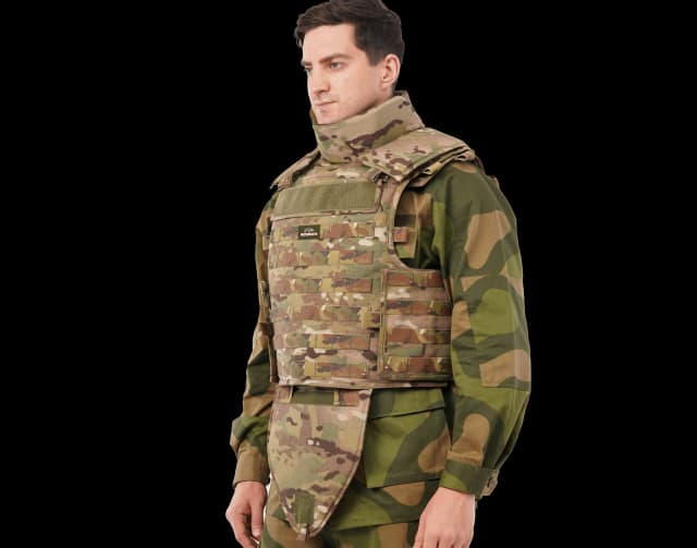 Man wearing Hard Shell Tactical Guardian Vest in camouflage with neck and groin protection panels.