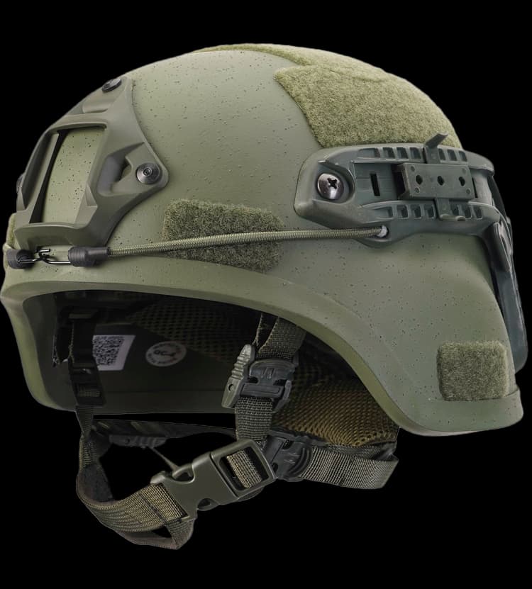 Angled close-up of green MICH helmet with NVG mount, side rail, Velcro panels, and padded chin strap.