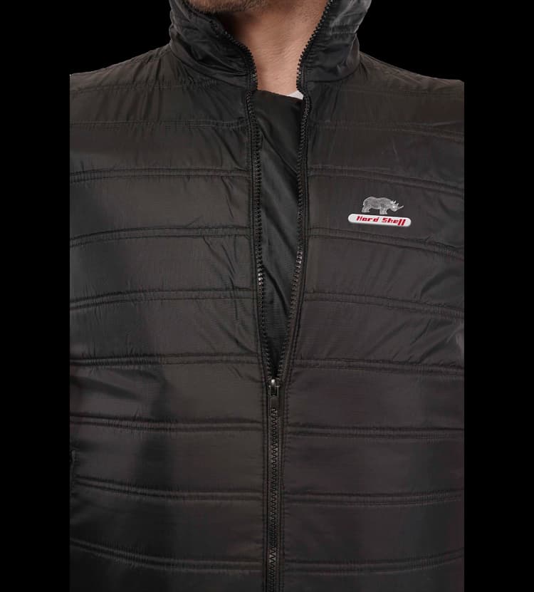 Close-up of Hard Shell black Winter Turf Vest showing front zipper, quilted texture, and logo detail.